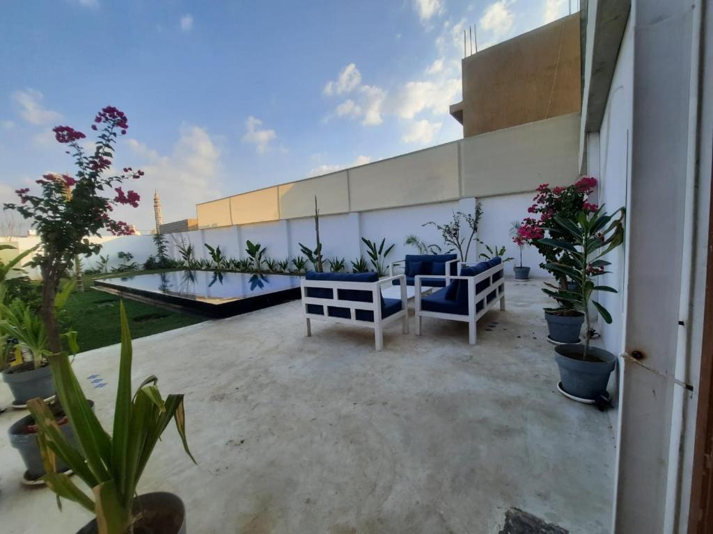 a patio with blue chairs and potted plants on a building at شاليه مزدانة in Makkah