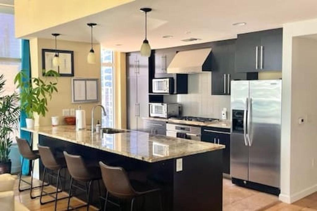 a kitchen with a large island with bar stools at Luxe 1BR plus Den near Little Italy Gem in San Diego