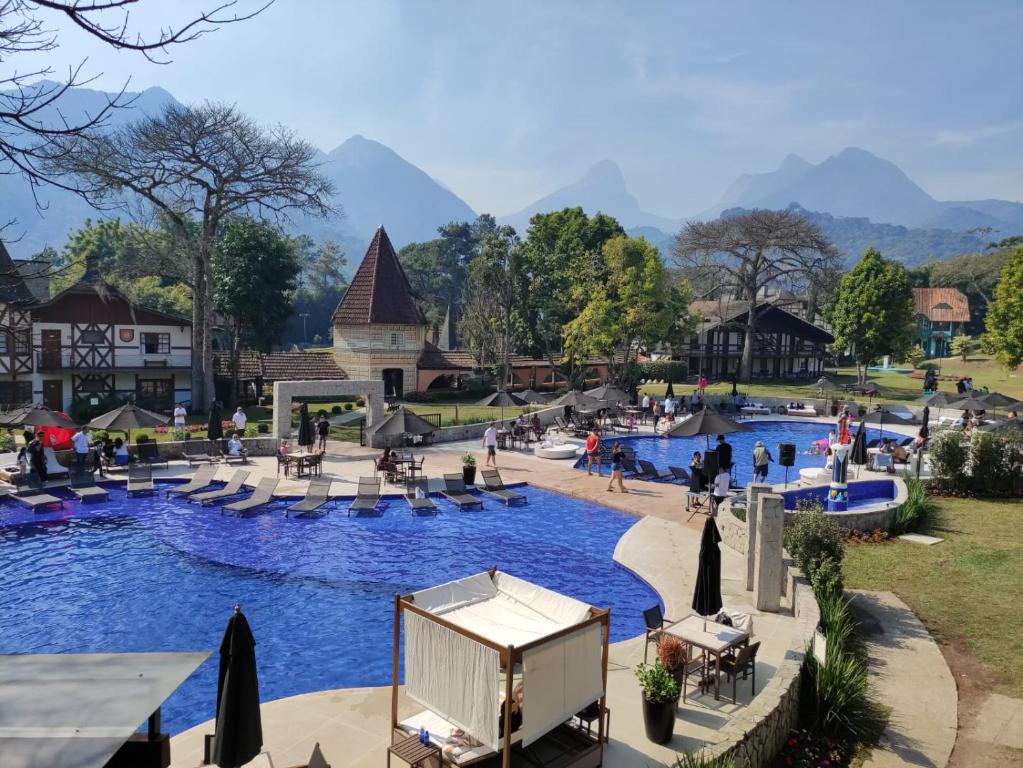 uma piscina num resort com pessoas sentadas à sua volta em Village Le Canton em Teresópolis