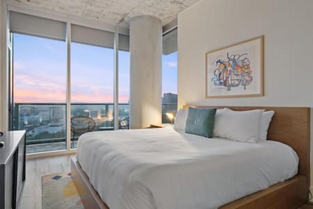 a bedroom with a large bed with a large window at 2BR Lux Highrise + Austin + Vibrant Rainey St in Austin
