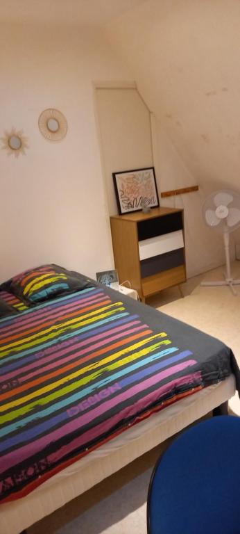 - une chambre avec un lit et une couverture rayée colorée dans l'établissement Saint Georges, à Villaines-sous-Lucé