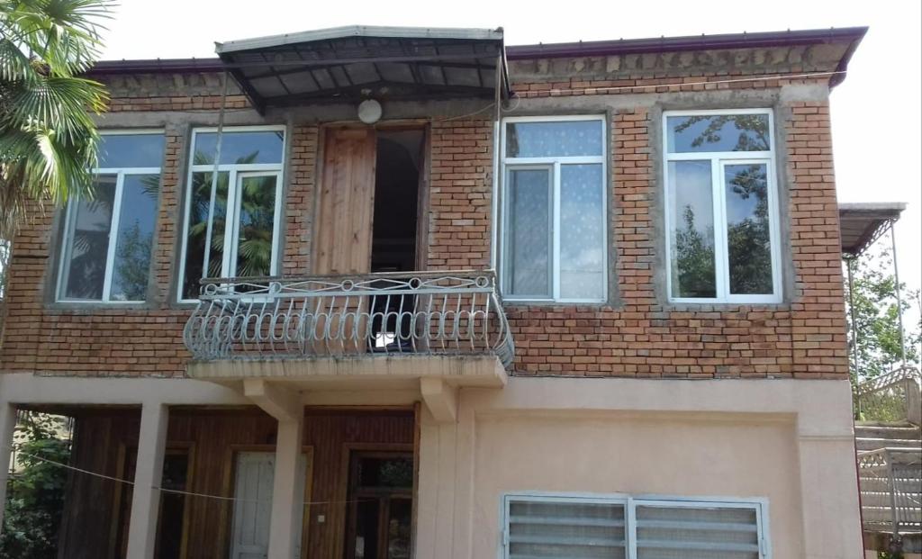 a brick house with a balcony and a porch at Cozy home in Zugdidi