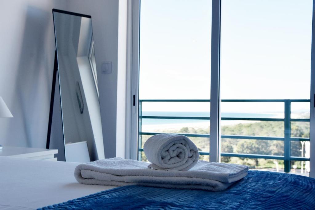 uma pilha de toalhas sentadas numa cama com uma janela em Beach House em Monte Gordo