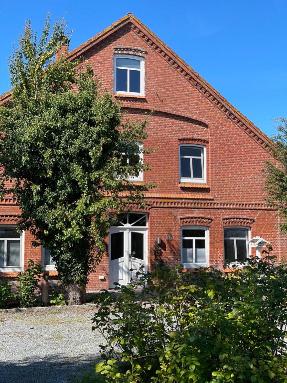 a brick building with a tree in front of it at Hof Steinhütten Boutique Apartments in Westerhever