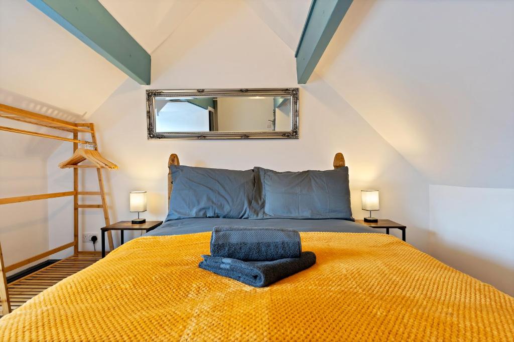 1 dormitorio con cama amarilla y espejo en la pared en Sally’s Cottage - Uttoxeter: Close to Alton Towers en Uttoxeter