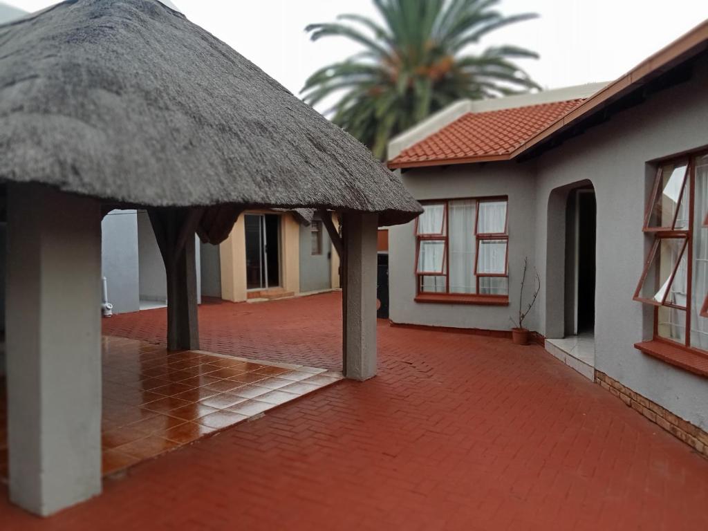a house with a thatch roof and a red brick floor at Moonlight Guest House in Benoni