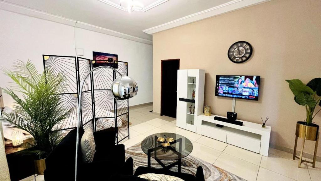 a living room with a tv and a glass table at Large studio at your disposal in Abidjan in Cocody