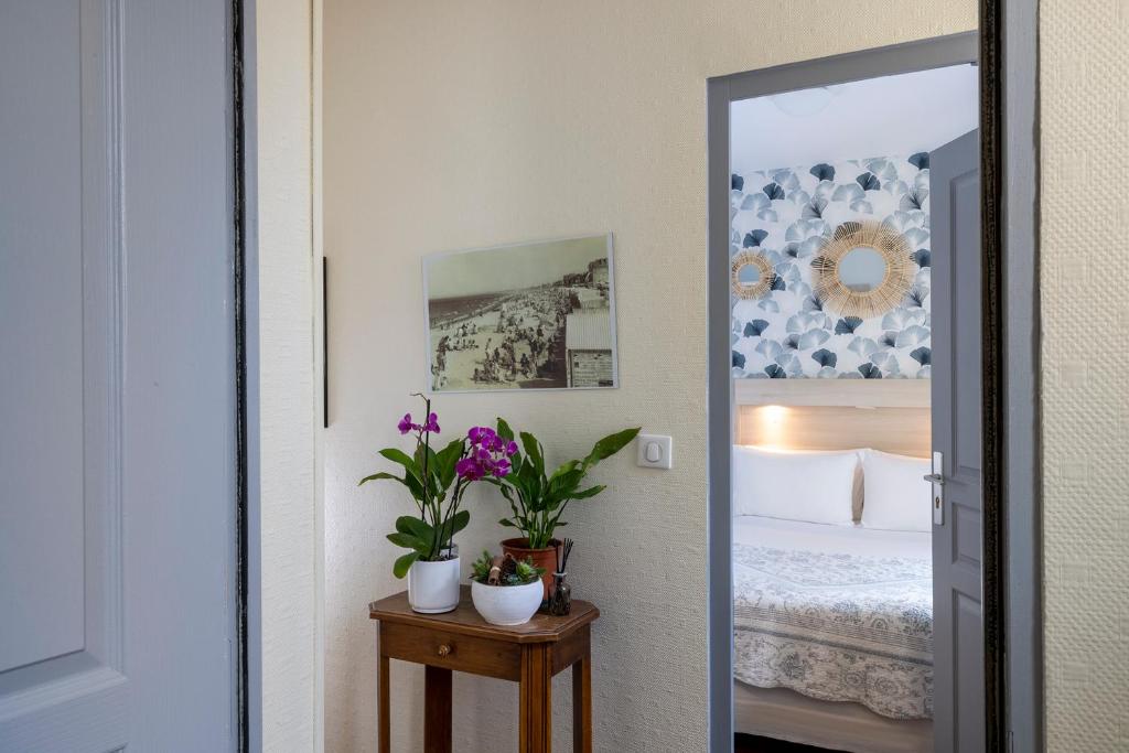 a bedroom with a bed and two potted plants at Hôtel de Lion sur Mer in Lion-sur-Mer