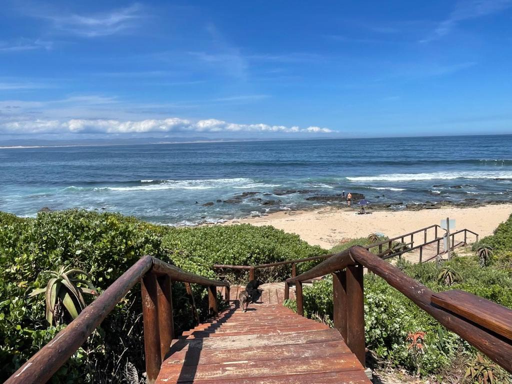 a wooden boardwalk leading to a beach with the ocean at Aloe Studio in Jeffreys Bay