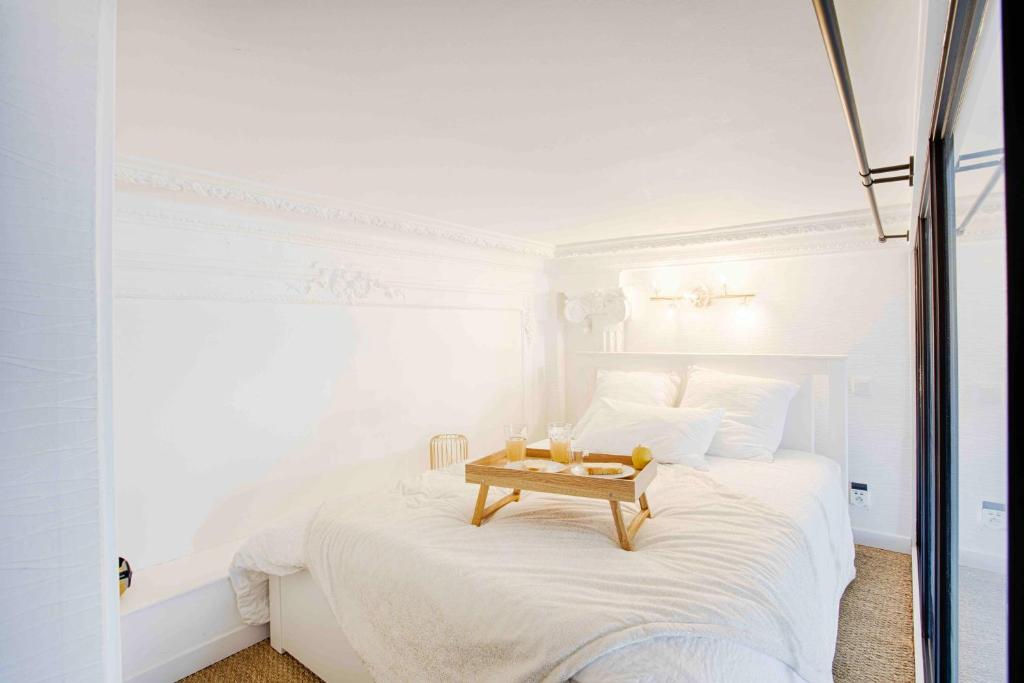 a white bedroom with a bed with a tray on it at WELC&#39;HOME IN HOULGATE - Vue et accès direct sur mer in Houlgate