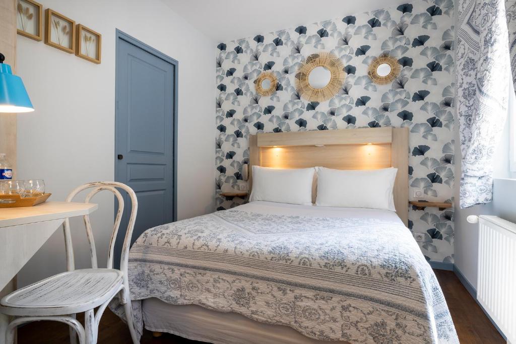 a small bedroom with a bed and a table at Hôtel de Lion sur Mer in Lion-sur-Mer