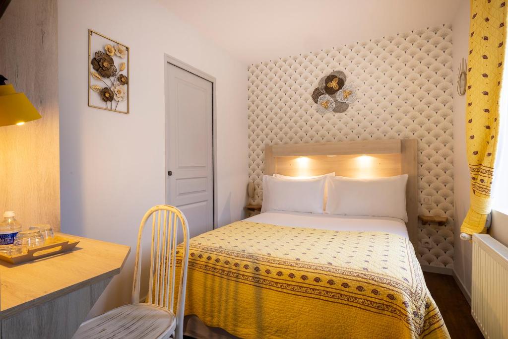 a small bedroom with a bed and a desk at Hôtel de Lion sur Mer in Lion-sur-Mer