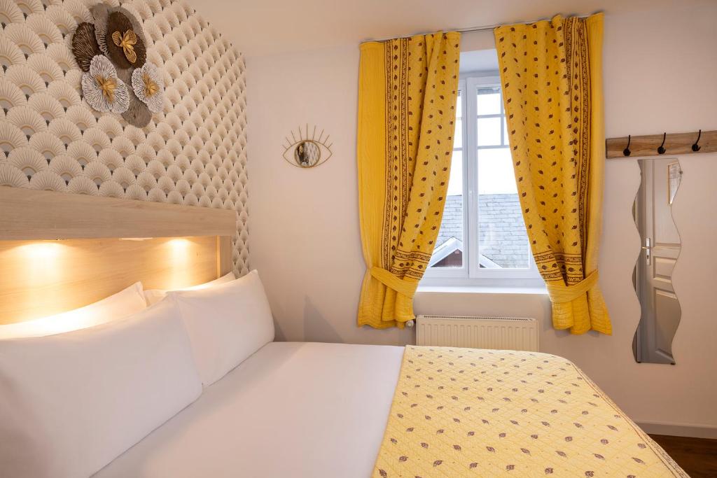 a bedroom with a bed and a window with yellow curtains at Hôtel de Lion sur Mer in Lion-sur-Mer