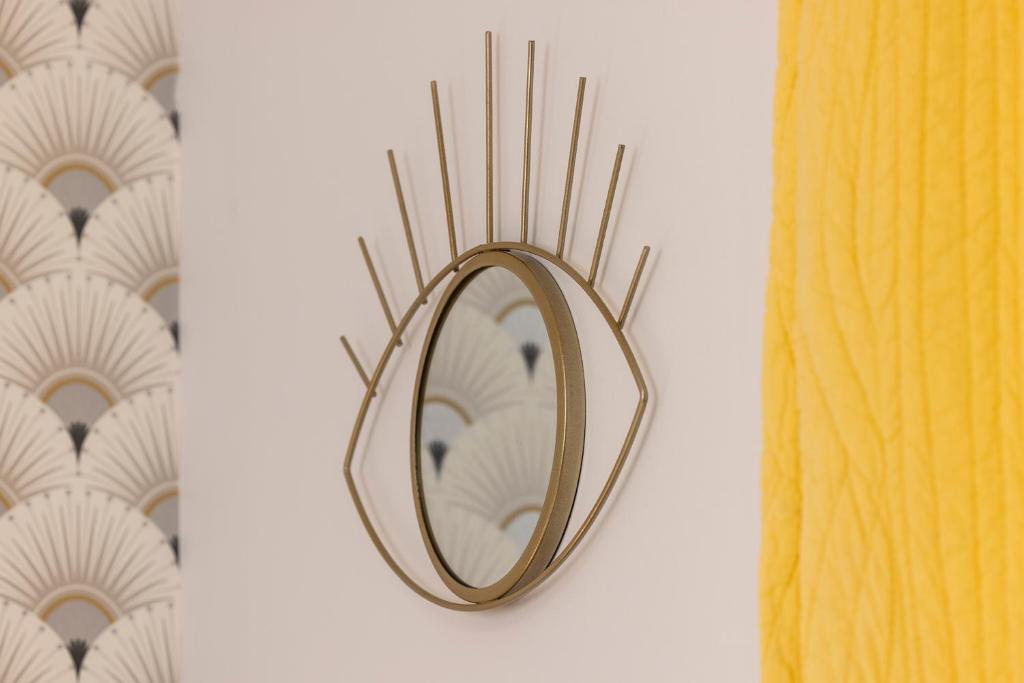 a mirror on a wall next to a yellow curtain at Hôtel de Lion sur Mer in Lion-sur-Mer