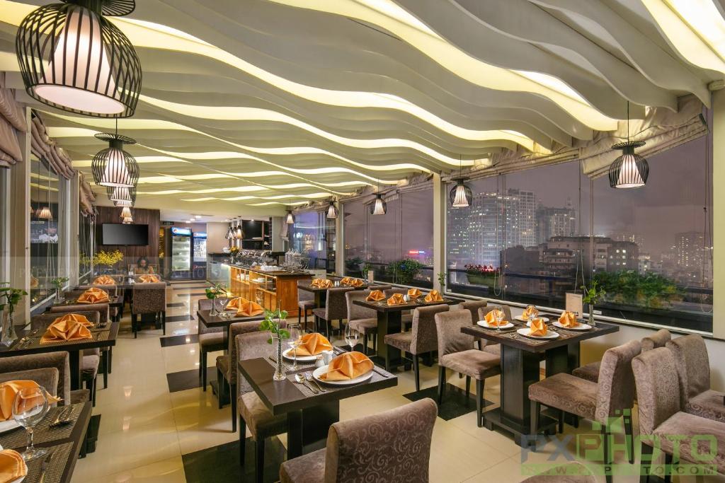 een restaurant met tafels en stoelen en uitzicht op de stad bij Parkside Sunline Hotel in Hanoi