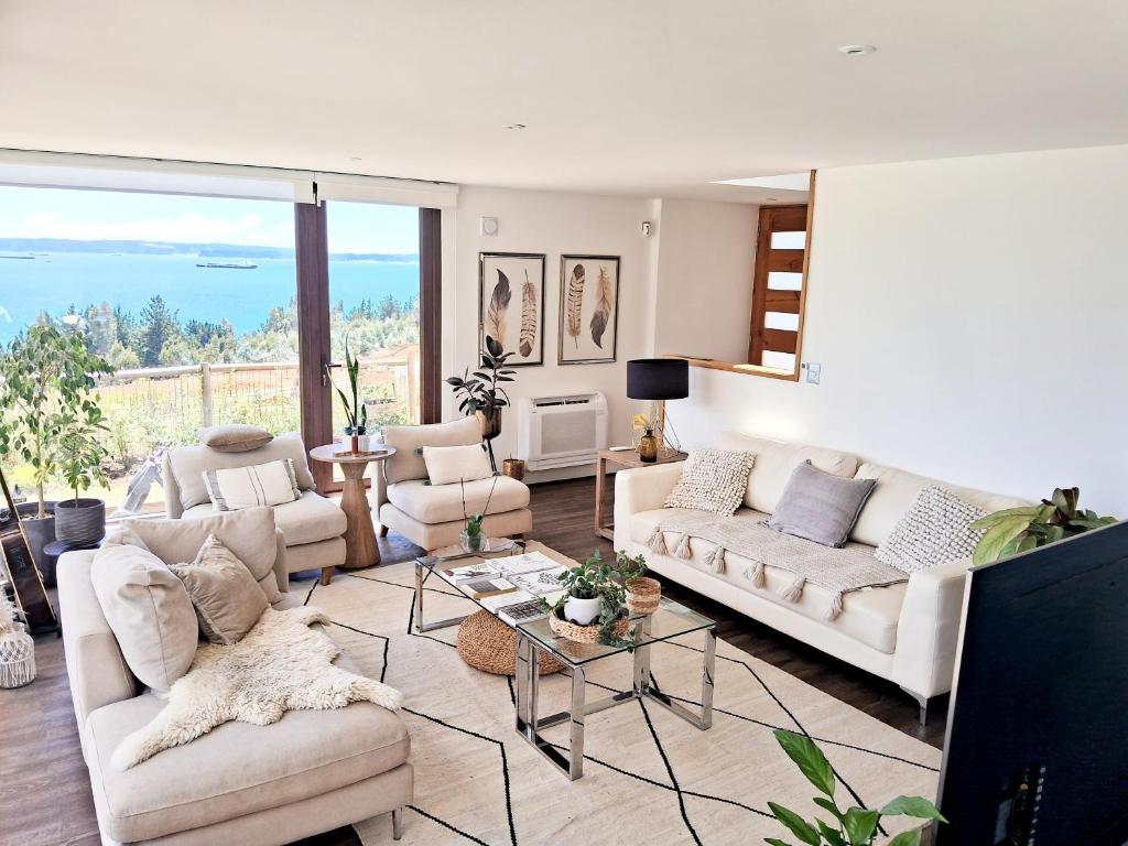 a living room with white furniture and a large window at VILLA THE SUN in Concepción