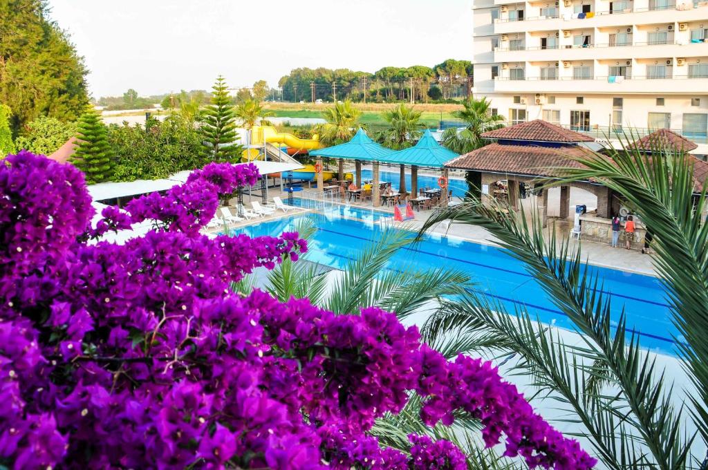 una imagen de una piscina del complejo con flores púrpuras en Belkon Hotel en Belek