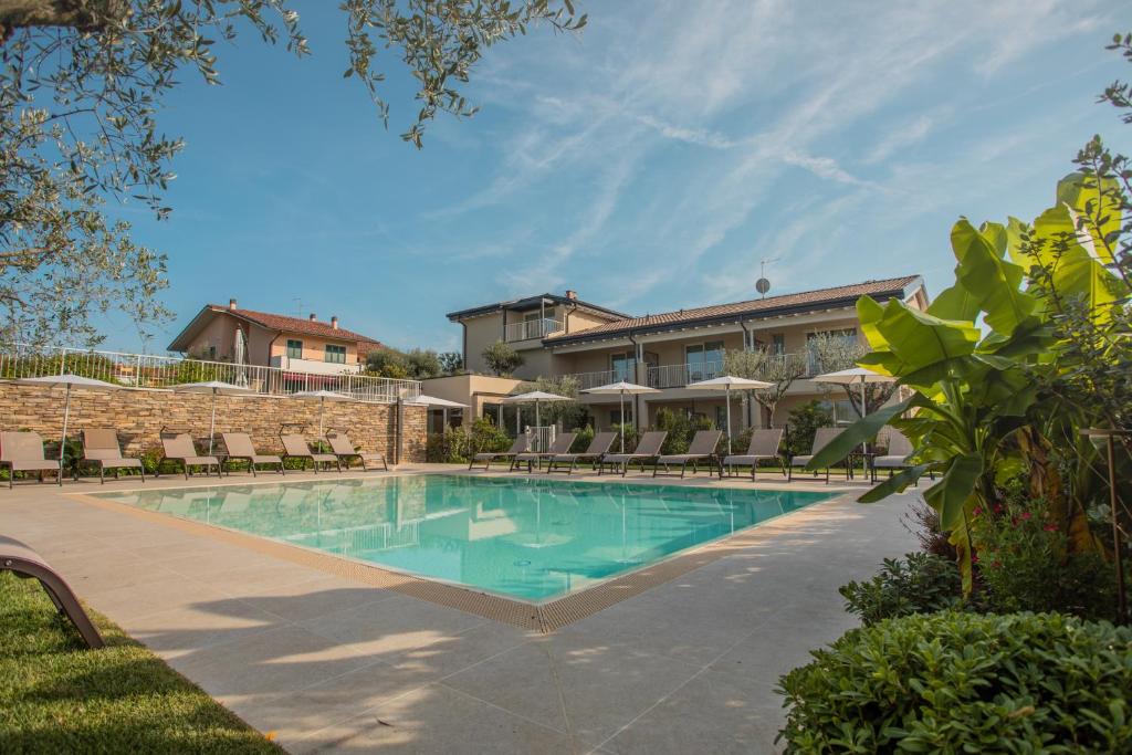 a swimming pool with chairs and a building at Re Ottone Rooms in Lazise