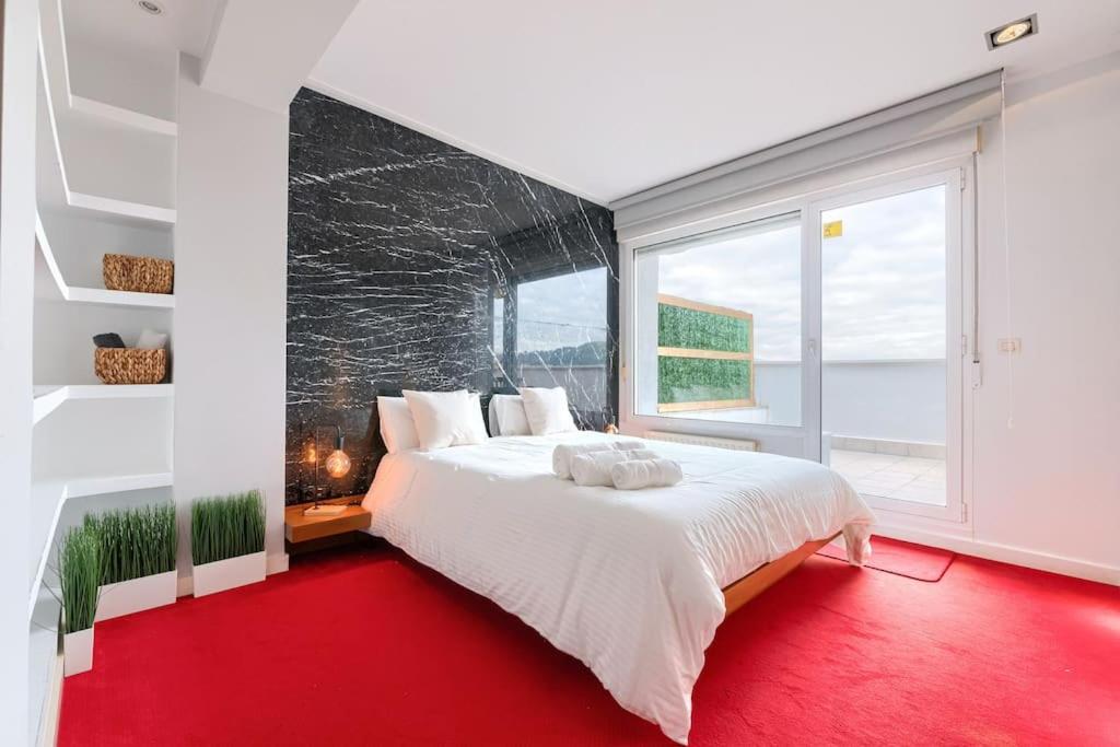 um quarto com uma grande cama branca e um tapete vermelho em Derio Aeropuerto em Derio