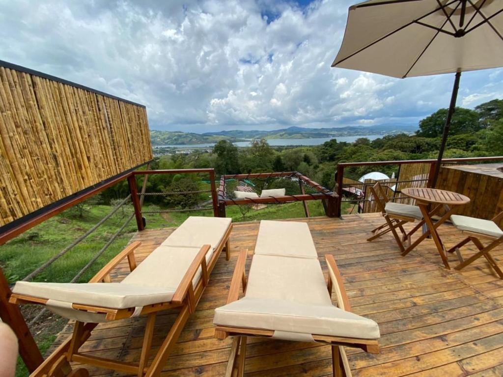 a deck with two chairs and an umbrella at MACA GLAMPING in Calima