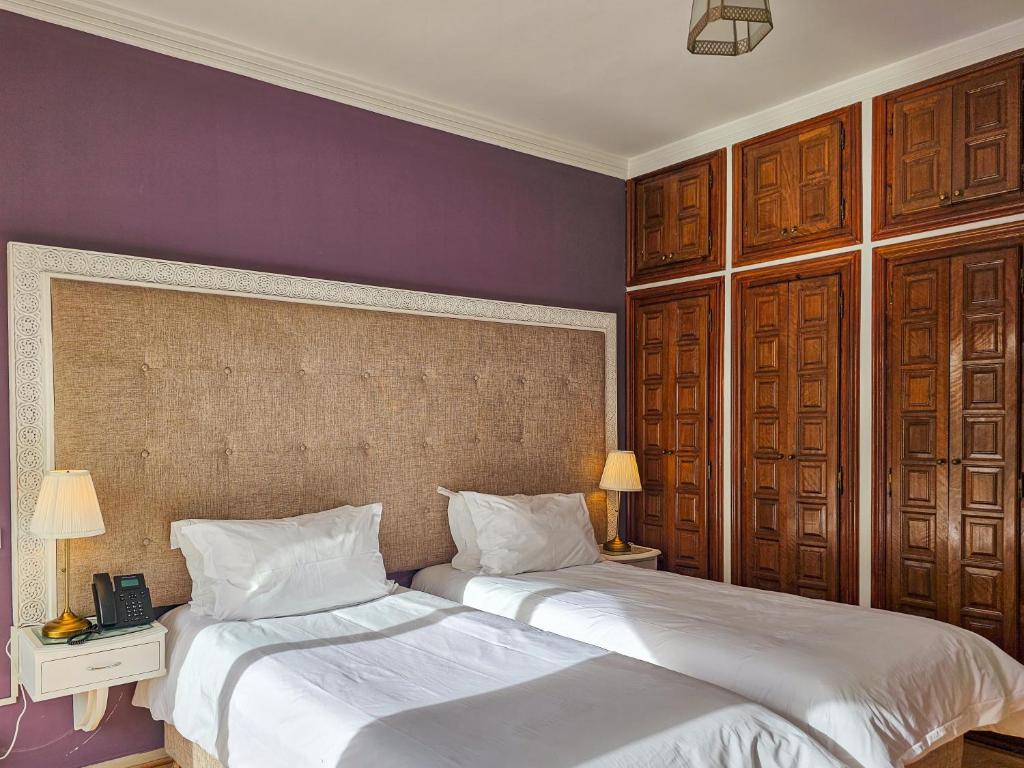 2 camas en un dormitorio con paredes moradas en Hôtel L'Hacienda, en Rabat