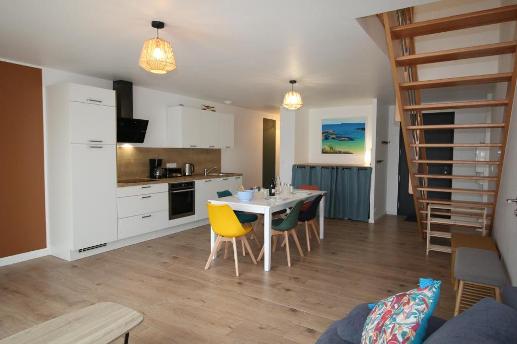 a kitchen and dining room with a table and yellow chairs at Maison neuve proche de la plage 3 chambres / accès PMR / Parking in Ploemeur