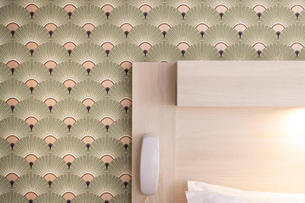 a bedroom with a gold and white wallpaper at Hôtel de Lion sur Mer in Lion-sur-Mer