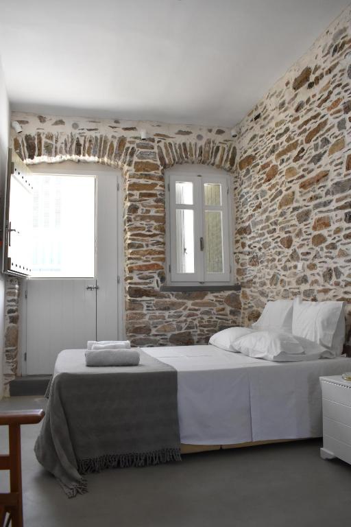 ein Schlafzimmer mit einem großen Bett in einer Ziegelwand in der Unterkunft Chora Cozy Studios in Kythnos