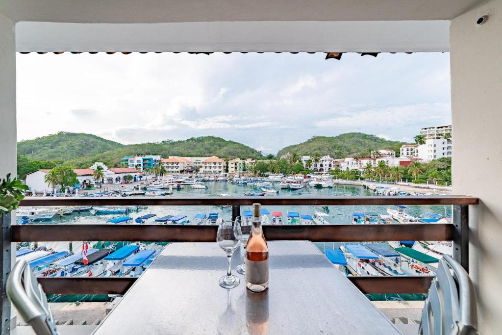 a table with wine glasses on a balcony with a view of a harbor at 3027 - Santa Cruz Condo in Santa Cruz Huatulco