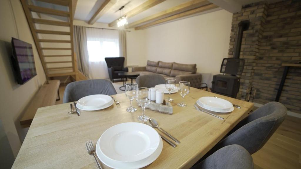 een houten tafel met borden en wijnglazen erop bij Apartman Trebevic-Sarajevo in Dovlići