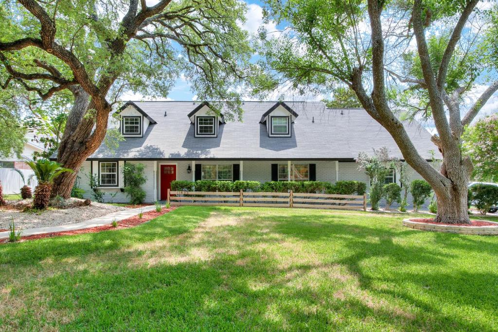 a white house with a red door and a yard at Cactus Club - A Birdy Vacation Rental in San Antonio