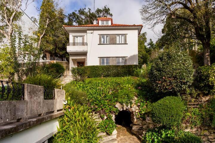 uma grande casa branca com um jardim em frente em Lanui Guest House em Sintra