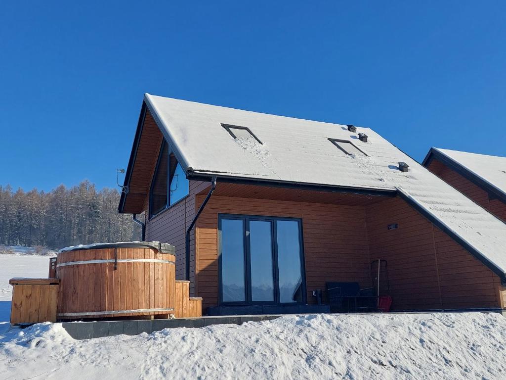a house with a hot tub in the snow at COSY CABINS - las, jezioro, góry, prywatna sauna, balia, tężnia in Kluszkowce