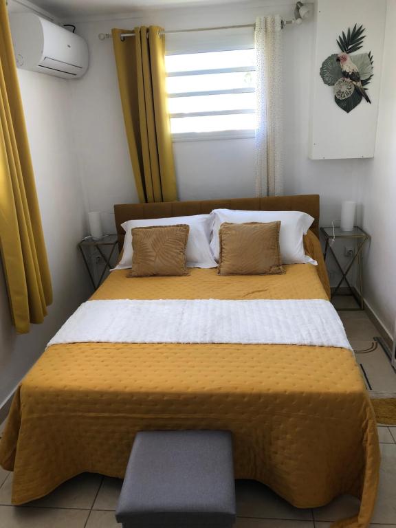 sypialnia z dużym żółtym łóżkiem i oknem w obiekcie Chez Laurenn w mieście Le Carbet