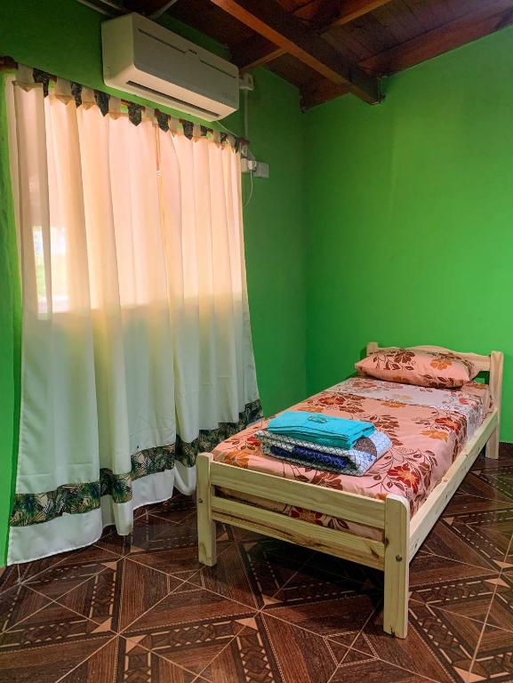 Cama pequeña en habitación verde con ventana en hospedaje don mario en San Ignacio