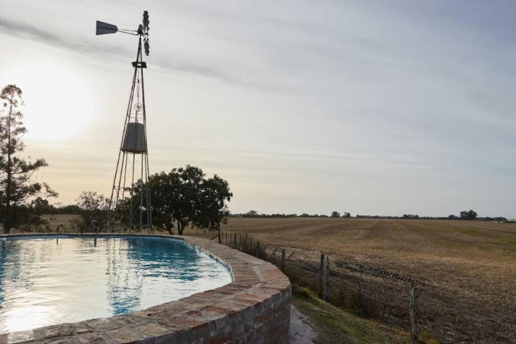 eine Windmühle und ein Schwimmbad auf einem Feld in der Unterkunft Hestia At San Antonio De Areco I Estancia Paraso in San Antonio de Areco