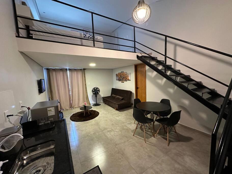 a living room with a staircase and a table and chairs at Apartamento/Loft 06 em Cabo Frio in Cabo Frio