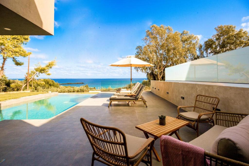 an outdoor patio with a table and chairs and a pool at Luxury Villa Mon I Vassilikos in Vasilikos