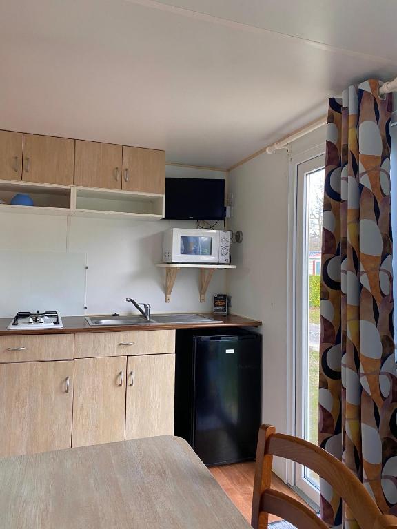 - une cuisine avec une table et un four micro-ondes dans l'établissement Mobil-home mitoyen 1 chambre, à Angicourt