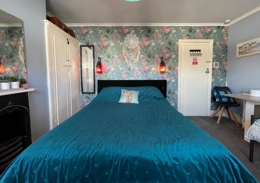 1 dormitorio con cama azul y papel pintado con motivos florales en Large Room with own TV and cereal and toast breakfast in Newhaven en Tarring Neville