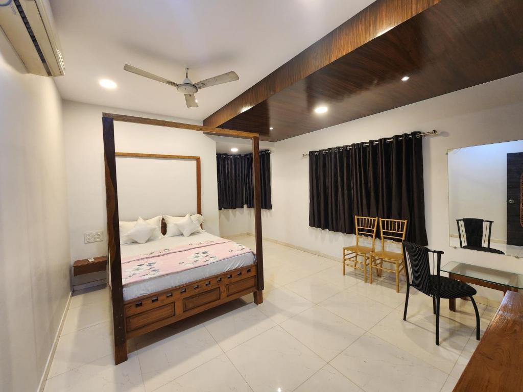 a bedroom with a bed and a table and a desk at Kuber hotel in Valsad