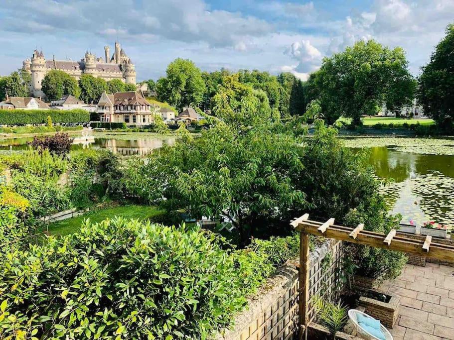 uma vista para um parque com um lago e um castelo em Maison de charme avec vue sur château em Pierrefonds