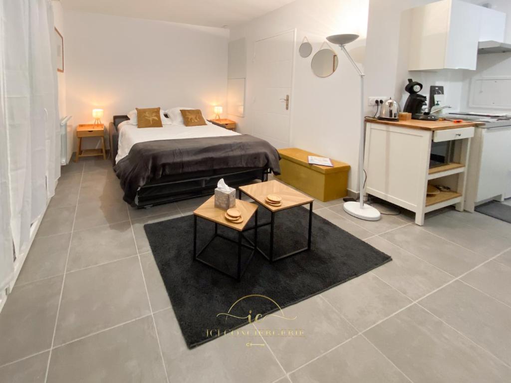 a bedroom with a bed and a table and a kitchen at Le Jardin Rambolitain - Terrasse et Parking in Rambouillet