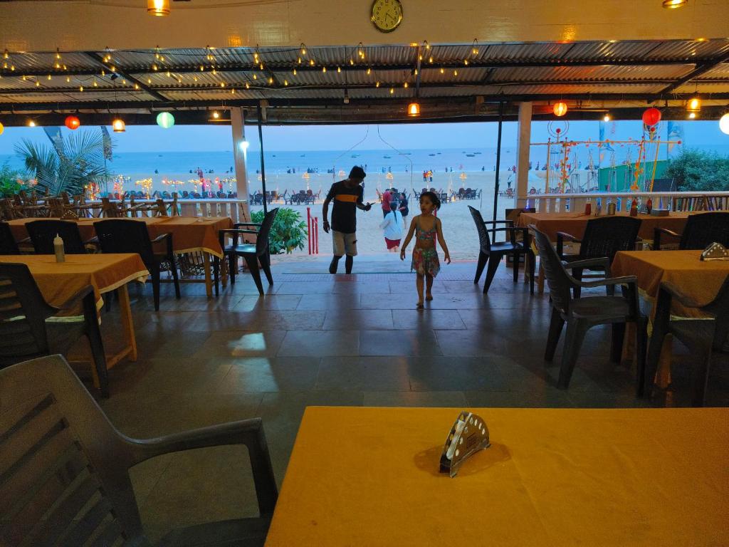 um homem e uma criança a andar por um restaurante em Oceanside Beach House-By Roseal em Baga