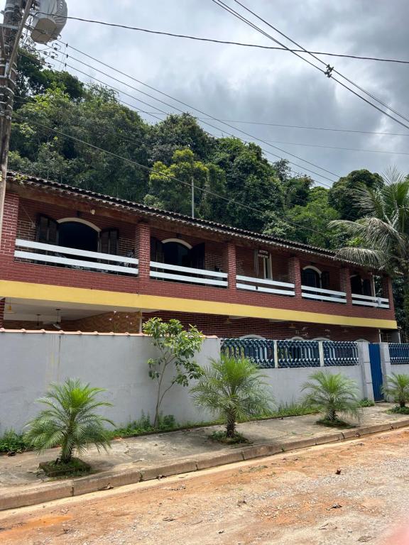 un edificio de ladrillo con palmeras delante de él en Recanto mato verde, en Caraguatatuba