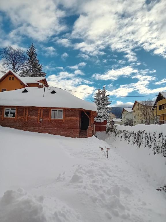 a house with snow on the ground in front of it at Casuta Azughia in Azuga