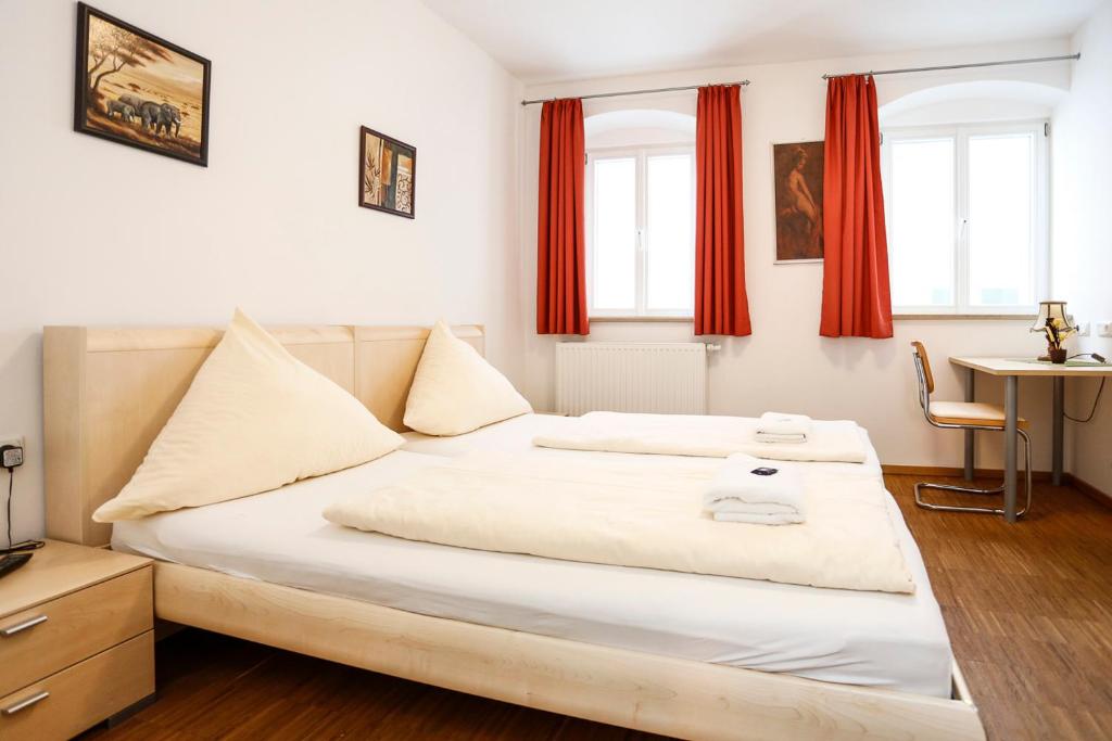 Schlafzimmer mit einem großen weißen Bett und roten Vorhängen in der Unterkunft Altstadtpension Friedberg in Friedberg
