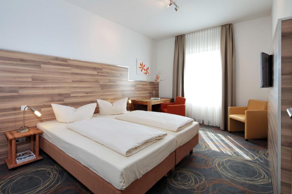 una habitación de hotel con una cama grande y una silla en Petul Apart Hotel Residenz, en Essen