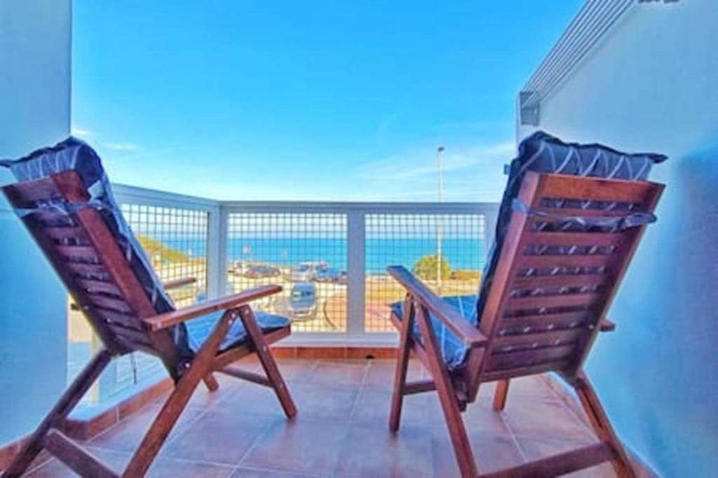 twee stoelen op een balkon met uitzicht op een luchthaven bij Apartment Sol Vinaròs con AA Wi-Fi a primera línea y vistas al mar. in Vinarós