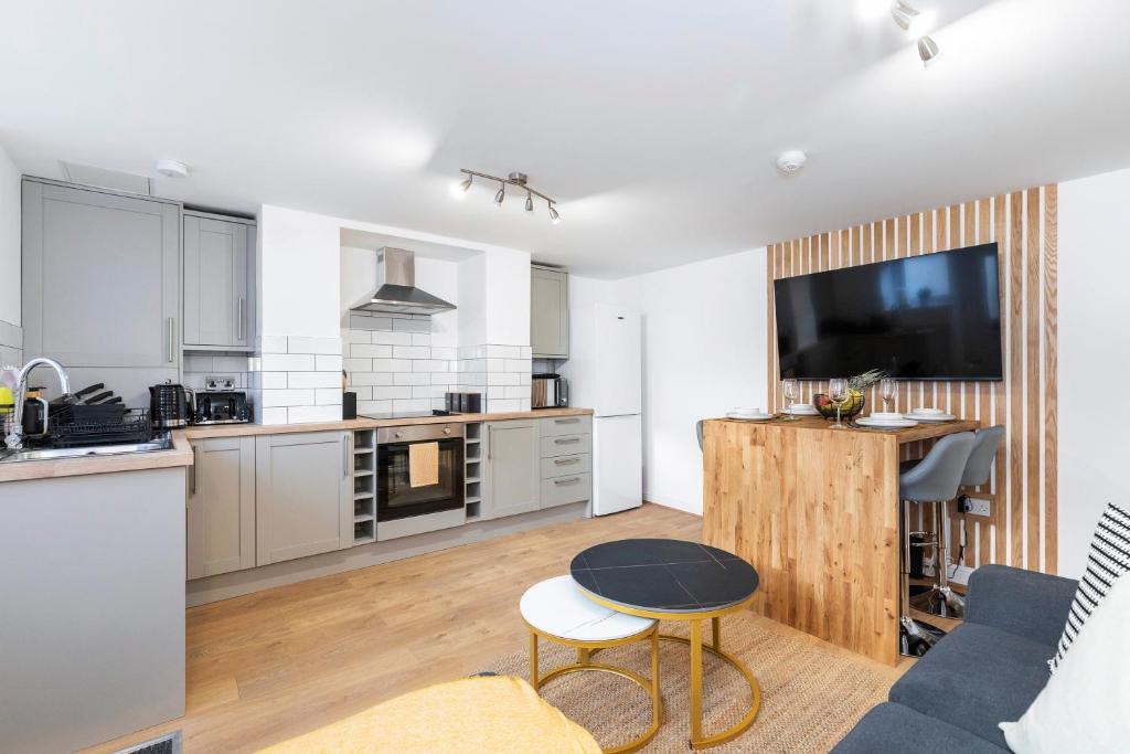 uma cozinha e sala de estar com um sofá e uma televisão em Luxury Two Bed Apartment with 55in TVs and Netflix em Headingley